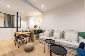 Una sala moderna con un sofá, una mesa de comedor, sillas, una mesita de centro y una alfombra.