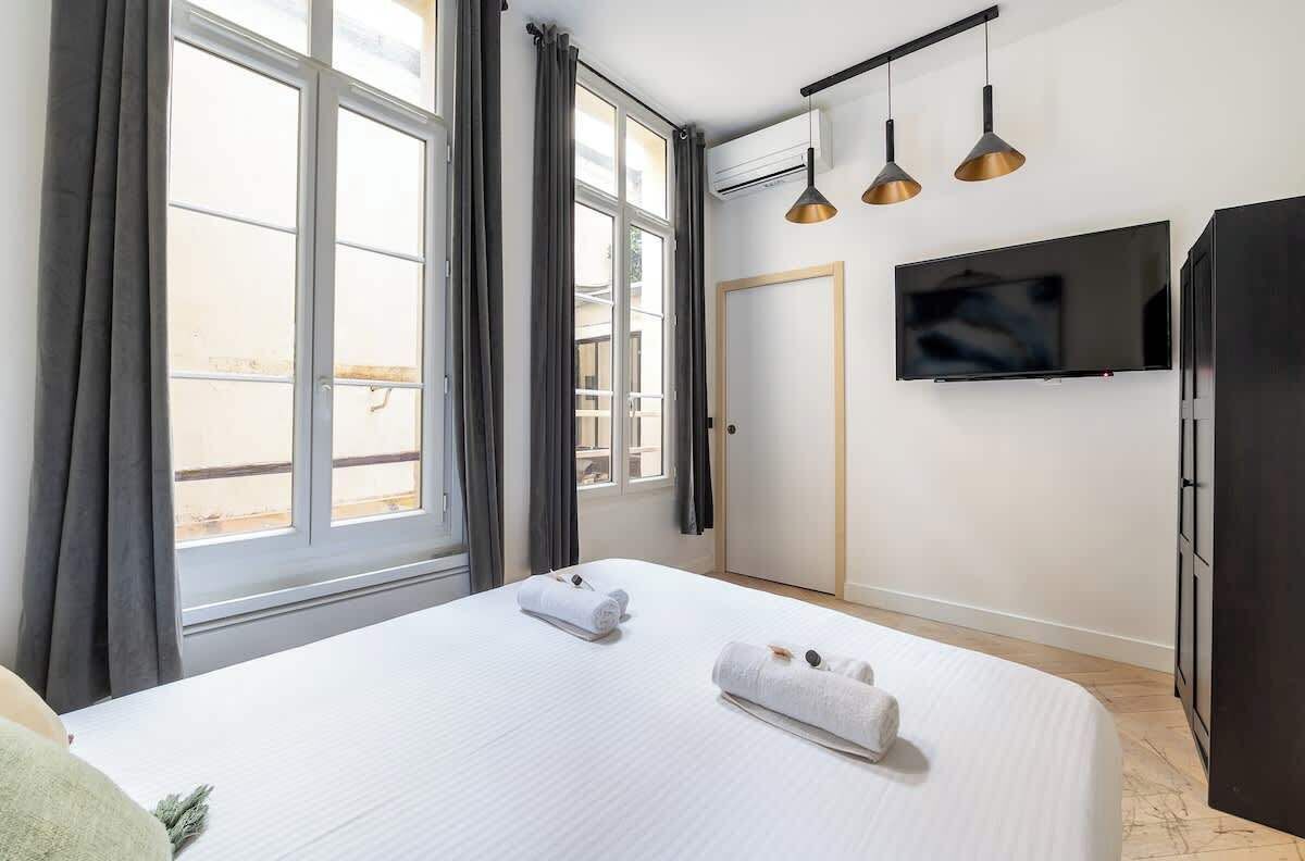 Une chambre d’hôtel avec un lit, deux serviettes, une télévision et une armoire.