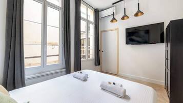 Une chambre d’hôtel avec un lit, deux serviettes, une télévision et une armoire.