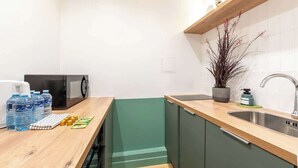 Ett kök med en bänkskiva i trä, en inbyggd diskmaskin, ett handfat och en krukväxt.