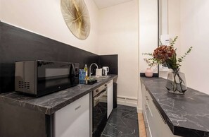 Una cocina moderna con un microondas negro, un lavamanos y un florero con flores en la encimera.