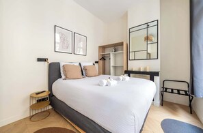 Een keurig opgemaakt slaapkamer met een bed, nachtkastjes, een garderobe en een spiegel.