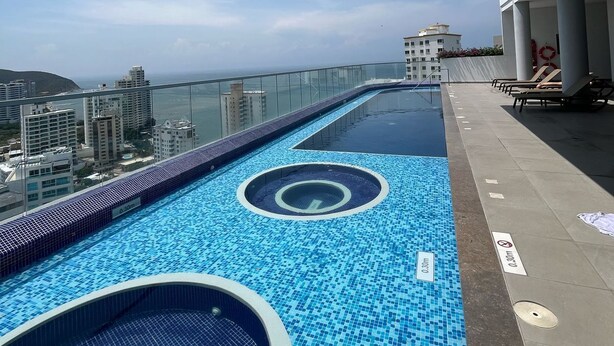 Une piscine à débordement située sur le toit, offrant une vue dégagée sur le paysage urbain et l’océan.