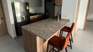 Une cuisine moderne dotée d’un îlot central avec un comptoir en granit, de meubles en bois et de deux tabourets de bar.