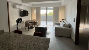 Un salon moderne comprenant un coin repas, un canapé, un téléviseur et un ventilateur.