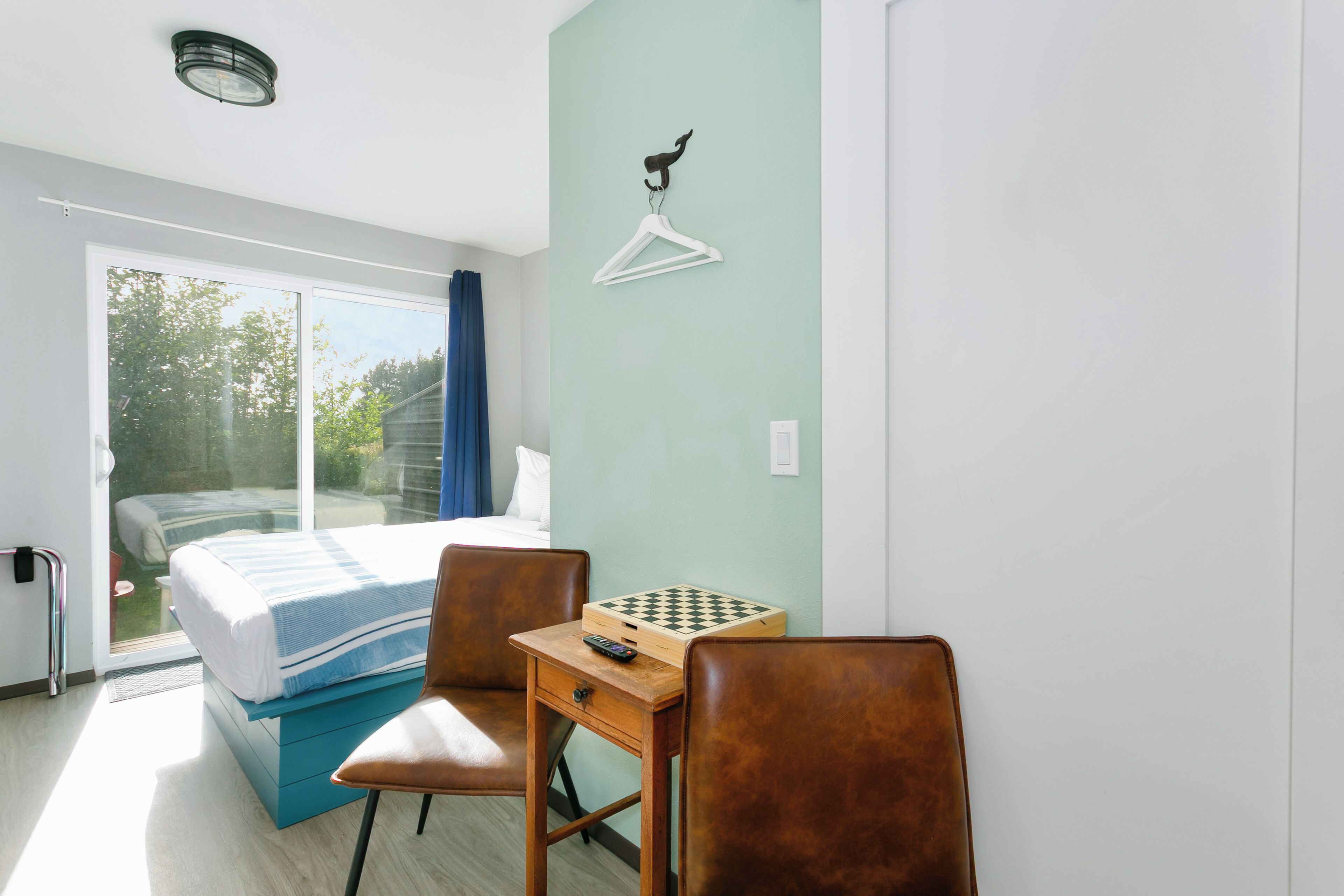 Ein Schlafzimmer mit einem Bett, einem Schreibtisch mit Schachbrett und einem Sessel.