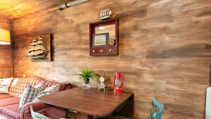 Una stanza accogliente con una parete in legno, un tavolo da pranzo in legno, un divano e una sedia.