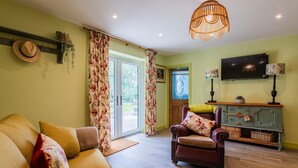 A living room with a sofa, armchair, and a television on a stand. - Garden View Barn, 1-bed, Sleeps 4 With Parking (Cowbridge)