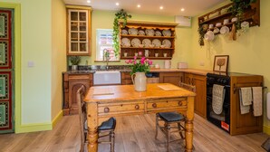 A kitchen with a wooden island, a sink, and a stove. There are chairs and a table in the center. - Garden View Barn, 1-bed, Sleeps 4 With Parking (Cowbridge)