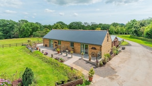 A wooden barn-style building with a sloped roof, surrounded by a well-maintained lawn and garden beds. - Garden View Barn, 1-bed, Sleeps 4 With Parking (Cowbridge)