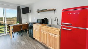 Une cuisine moderne avec un réfrigérateur Galanz rouge, des armoires en bois, un micro-ondes noir et un coin repas comprenant une table et des chaises.