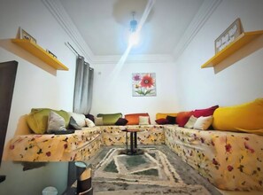 A living room with a sofa set, a coffee table, and a painting on the wall. - Mixed Comfort Dormitory (Marrakech)
