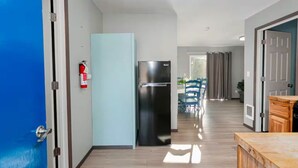 A modern kitchen with a black refrigerator, a blue door, and a fire extinguisher on the wall.