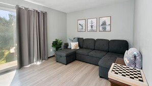 A modern living room with a sectional sofa, a chessboard, and three framed pictures on the wall.