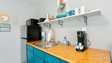 Een koelkast, kookgerei, borden en bestek, een eettafel