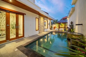 A modern house with a swimming pool, stone walls, and a statue. - 4BR Villa Uluwatu | Pool | 7 min to Melasti Beach | Rooftop Bar | Sunset Views | (Bali)
