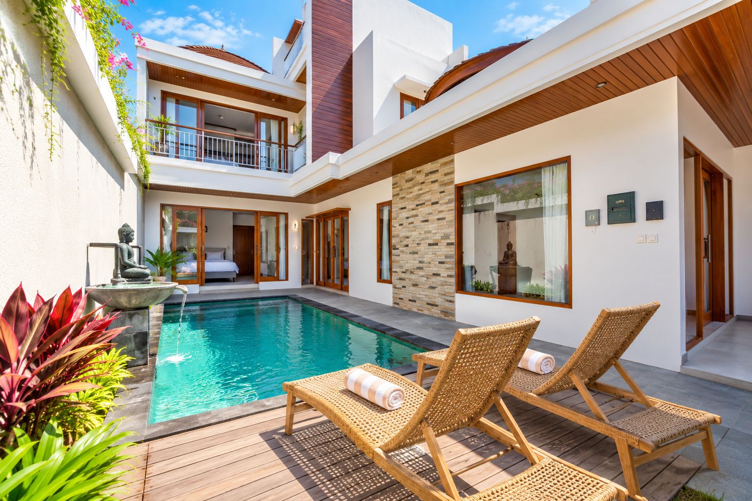 A modern poolside area with a clear pool, wooden deck, and lounge chairs.
