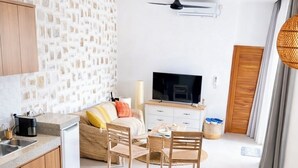 Eine moderne Küche mit Steinrückwand, Holzschränken, einem Essbereich mit Tisch und Stühlen, einem Fernseher und einem Deckenventilator.