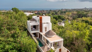 Ein modernes, zweistöckiges Haus mit Swimmingpool, umgeben von üppiger Vegetation und mit Blick auf eine reizvolle Landschaft.