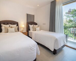 A hotel room with two beds, a nightstand, a lamp, and a balcony with a view. - 4BR Villa Uluwatu | Pool | 7 min to Melasti Beach | Rooftop Bar | Sunset Views | (Bali)