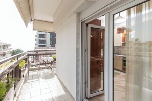 Enjoy dining or socializing on this modern balcony with a glass door leading to a kitchen area.