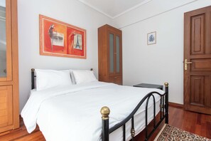 Cozy retreat with a neatly made bed, wooden wardrobe, and artwork above.