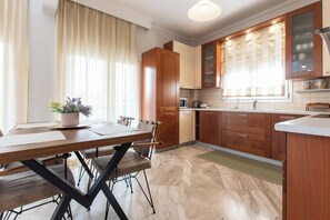 Enjoy cooking in this well-lit kitchen with a microwave, stainless steel sink, and wooden cabinets.