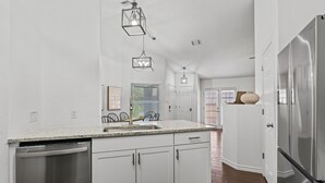 Una cocina moderna con armarios blancos, electrodomésticos de acero inoxidable y encimera de granito.