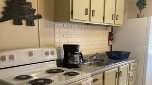 A kitchen with a white stove, a coffee maker, and light green cabinets. - Dino Den - Charming 1-bedroom apartment in Oneonta with WiFi, AC (Oneonta)