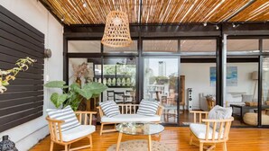 Un interior moderno con piso de madera, una mesa redonda de vidrio y dos sofás a rayas.