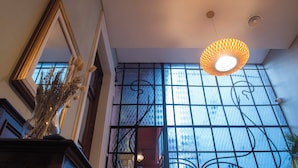 Una habitación con un ventanal grande, un espejo decorativo y una lámpara colgante.