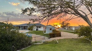 A residential area with houses, a grassy lawn, and a tree in the foreground. - Waterfront Family Retreat, heated pool, 2 miles from the Beach (Englewood)