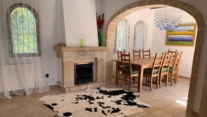 A room with a fireplace, a dining table with chairs, and a cowhide rug. - Casa Javea (Jávea)