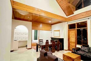 Relax in a spacious living area with a high ceiling, featuring a dining table and comfortable seating area.