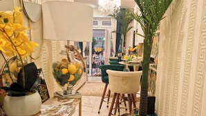 A hallway with a marble floor, a console table with decorative items, a mirror, and a green upholstered chair. - Vaticano 13 guesthouse (Rome)