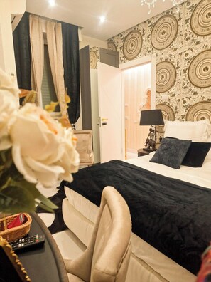 A bedroom with a bed, a nightstand, a lamp, a chair, and a wall with circular patterns. - Vaticano 13 guesthouse (Rome)