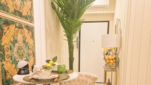 A dining area with a round table, two upholstered chairs, a potted plant, and a side table with a lamp and decorative items. - Vaticano 13 guesthouse (Rome)