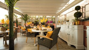 A covered patio area with wicker furniture, a dining table set for a meal, and a white cabinet with decorative items. - Vaticano 13 guesthouse (Rome)