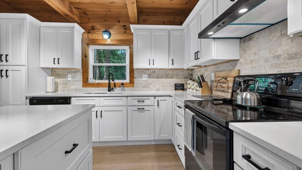 A modern kitchen with white cabinets, a stone backsplash, and a wooden ceiling. - Lakefront Lincoln Log home at Locke Lake Colony Association (Barnstead)