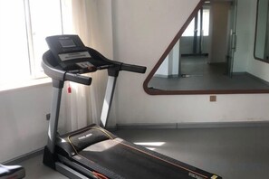 A treadmill in a room with a large mirror and a window. - Changchun Celebrity Hotel (Changchun)