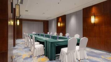 A conference room with a long table, white chairs, and a carpeted floor.