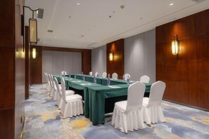 A conference room with a long table, white chairs, and a carpeted floor. - Changchun Celebrity Hotel (Changchun)