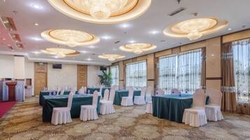 A banquet hall with round tables, chairs, and a red carpet.