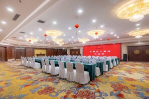 A conference room with round tables, white chairs, and a carpeted floor.