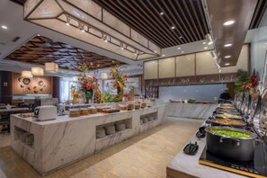 A modern kitchen with a marble island, a buffet setup, and decorative plants. - Changchun Celebrity Hotel (Changchun)