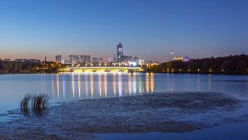 Una masa de agua tranquila que refleja las luces de la ciudad y un puente, con edificios al fondo.