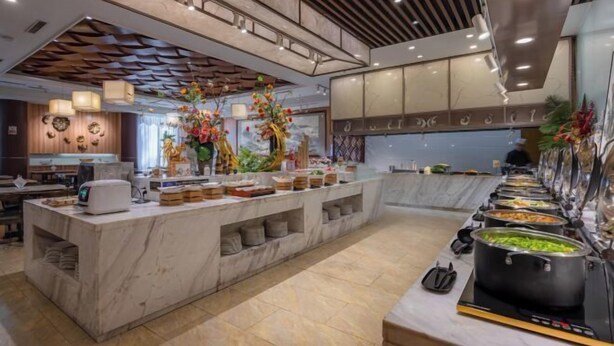 A modern hotel lobby with a marble reception desk, a buffet area with various food options, and decorative floral arrangements. - Changchun Celebrity Hotel (Changchun)