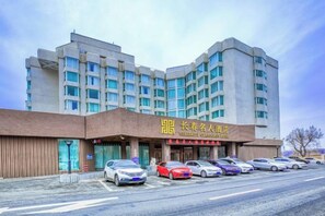 A multi-story hotel with a prominent entrance and a parking lot. - Changchun Celebrity Hotel (Changchun)