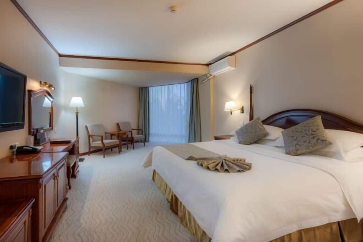 Une chambre d’hôtel avec un grand lit, un bureau équipé d’un ordinateur, une chaise et un téléviseur.