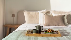 A bed with a wooden tray holding two black cups and a plate with fruit. - With pool, in Funchal - Acqua Residence II (Funchal)